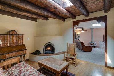 Small Sitting Room with Kiva Fireplace, Vigas, Hard Wood Floor looking into Den