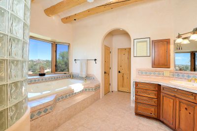 Master bath with separate vanities, a nautilus shaped shower, and whirlpool tub overlooking the sunset and stars