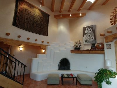 Dramatic 2 story fireplace sculpted of natural adobe rises to coved ceilings and clerestory windows