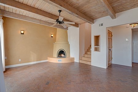 Brick floors and American Clay and Plaster walls a Kiva Fireplace in Living Room with Beam Ceilings