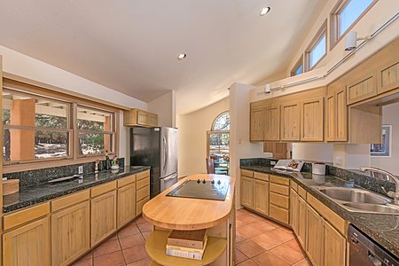 Kitchen with center island, granite counters, high canted ceiling and recessed & track lighting, and large windows facing the rear grounds