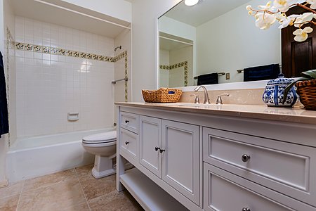 The Guest Bathroom Has a New Vanity with Soft Close Drawers New Dual Flush Toilet Mirror Light Sconce & Travertine Flooring 