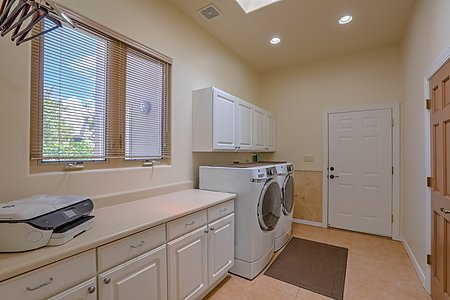 Oversized laundry room with storage closet and cabinetry 