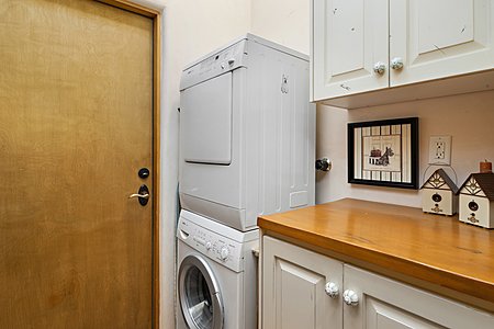 Laundry Room off Kitchen with Stacked W/D and Cabinets leading to Garage