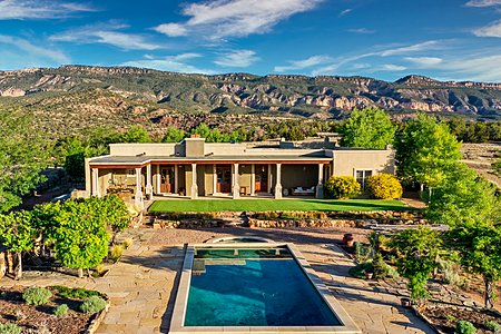 Adobe hacienda main house with a pool and National Forest in the background