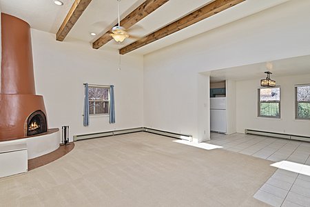 Living room with beams and a wood burning Kiva fireplace