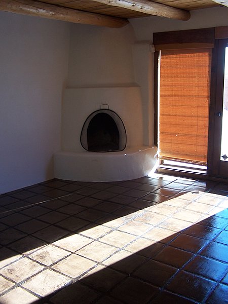 Kiva Fireplace, Vigas & Decking in ceiling and scored concrete flooring hallmarks of passive solar design.