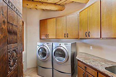Laundry room has two marble countertops along with built in cabinetry and utility sink.