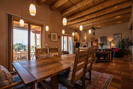View onto long Portal with view of Jemez from formal Dining room and Living room with a Kiva fireplace in the corner