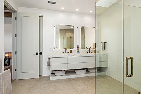 Primary bath with neolith countertops, custom cabinets, & illuminated mirrors