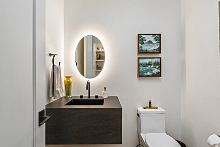 Powder room with a floating sink and illuminated mirror