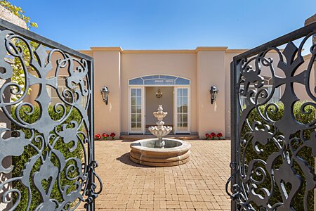 Looking through Iron Gates into Entry Courtyard with Decorative Fountain