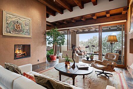 The living room has high ceilings, beams, fireplace and view