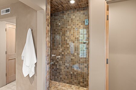 Tiled shower next to walk-in closet and primary suite