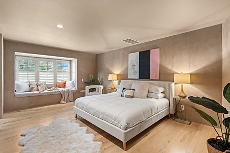 Primary bedroom with Plastered walls and whitewashed, hardwood floors in the primary bedroom.